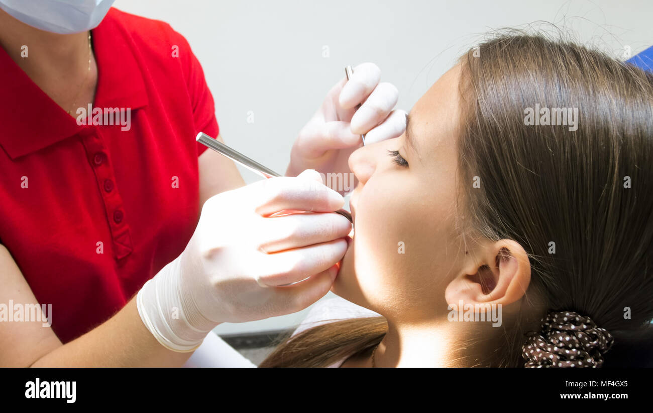 Closeup image of dentist hands in protective gloves inspecting oral cavity in girls mouth Stock Photo