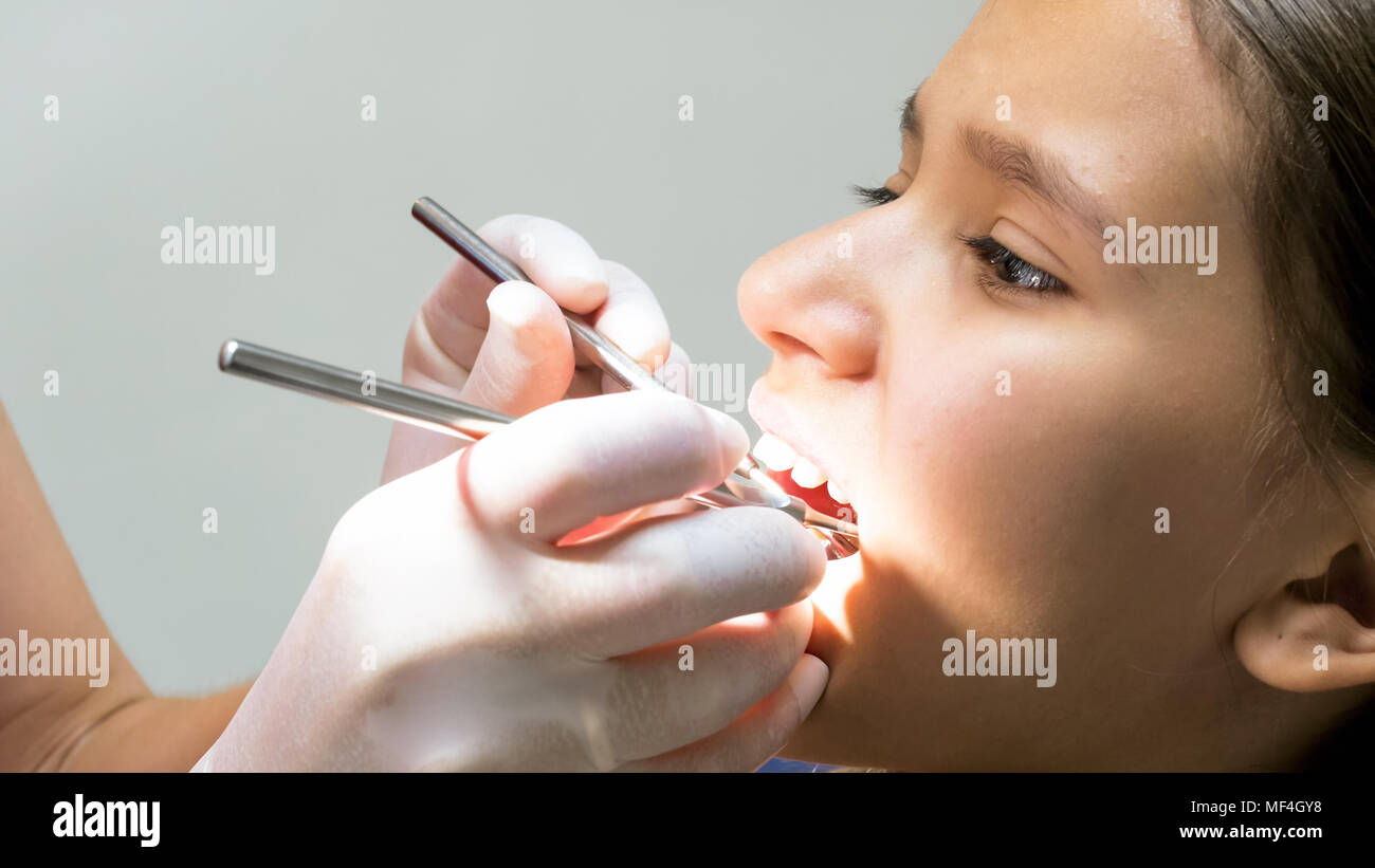 Closeup image of dentist inspecting girls teeth with instruments Stock Photo