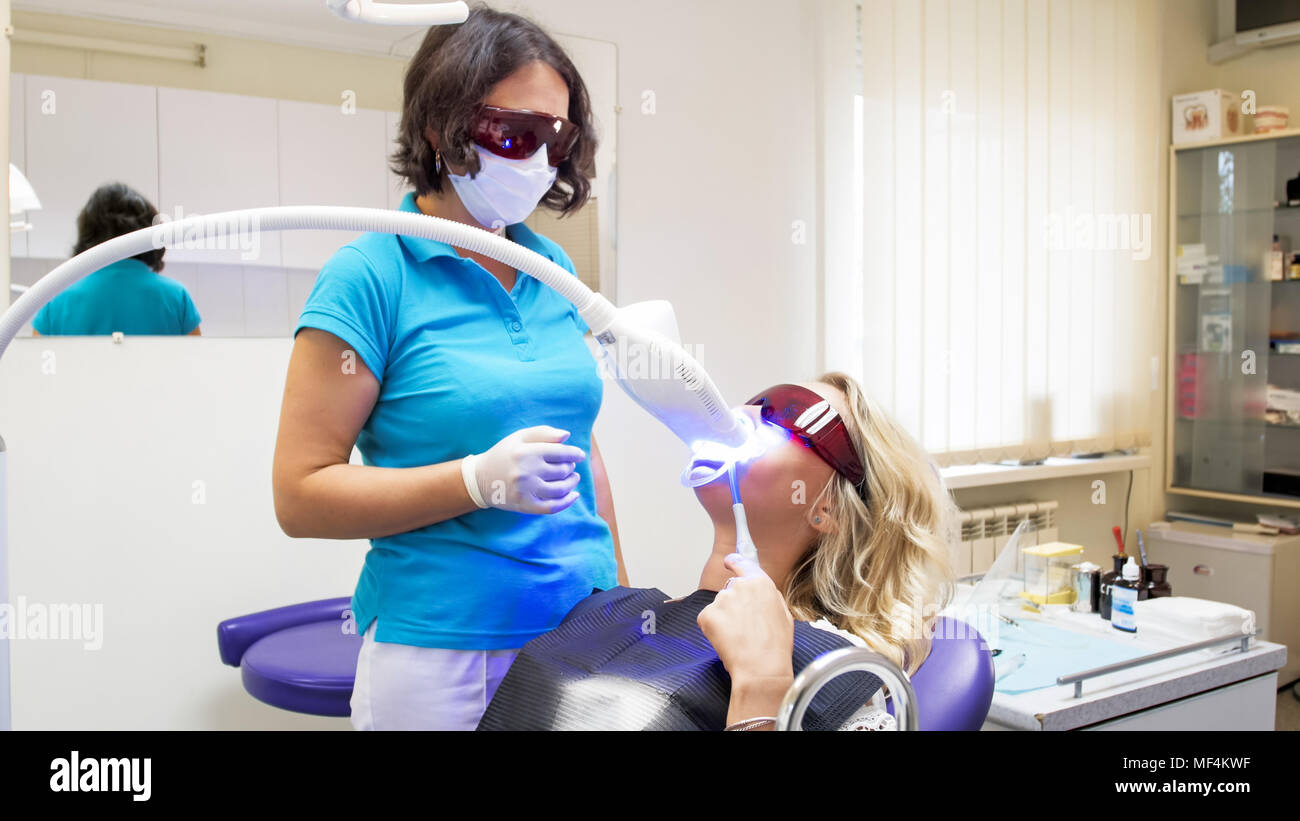 Young blonde woman sitting in dentist chair during teeth whitening