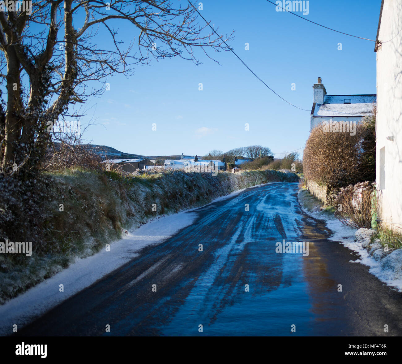 Snow melting on the road going up at Ballakilpheric Stock Photo