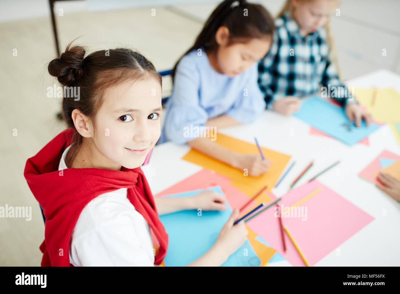 Portrait of pretty Caucasian girl smiling at camera while sitting with ...