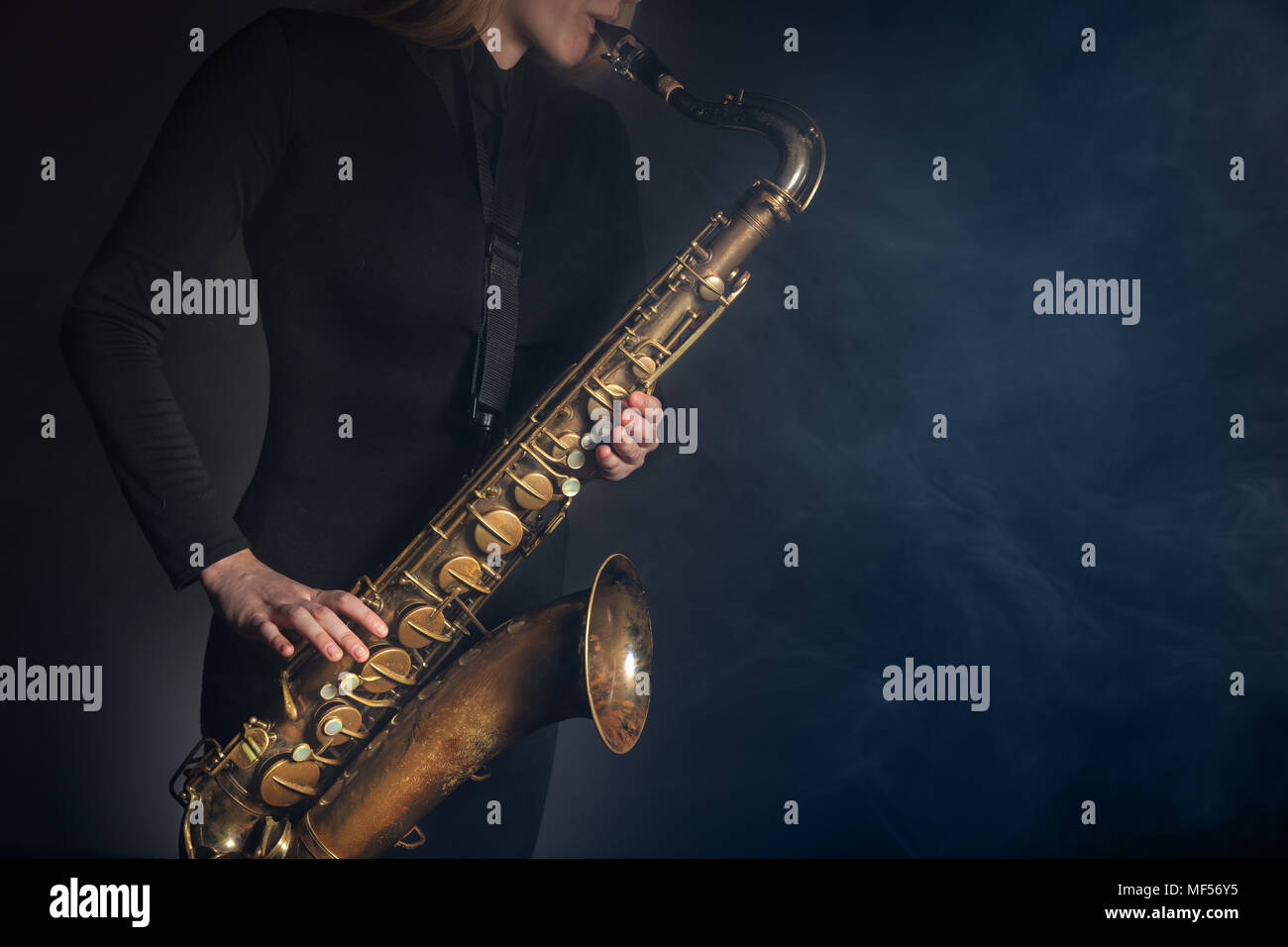 Saxophone player. Woman with saxophone on a dark background Stock Photo