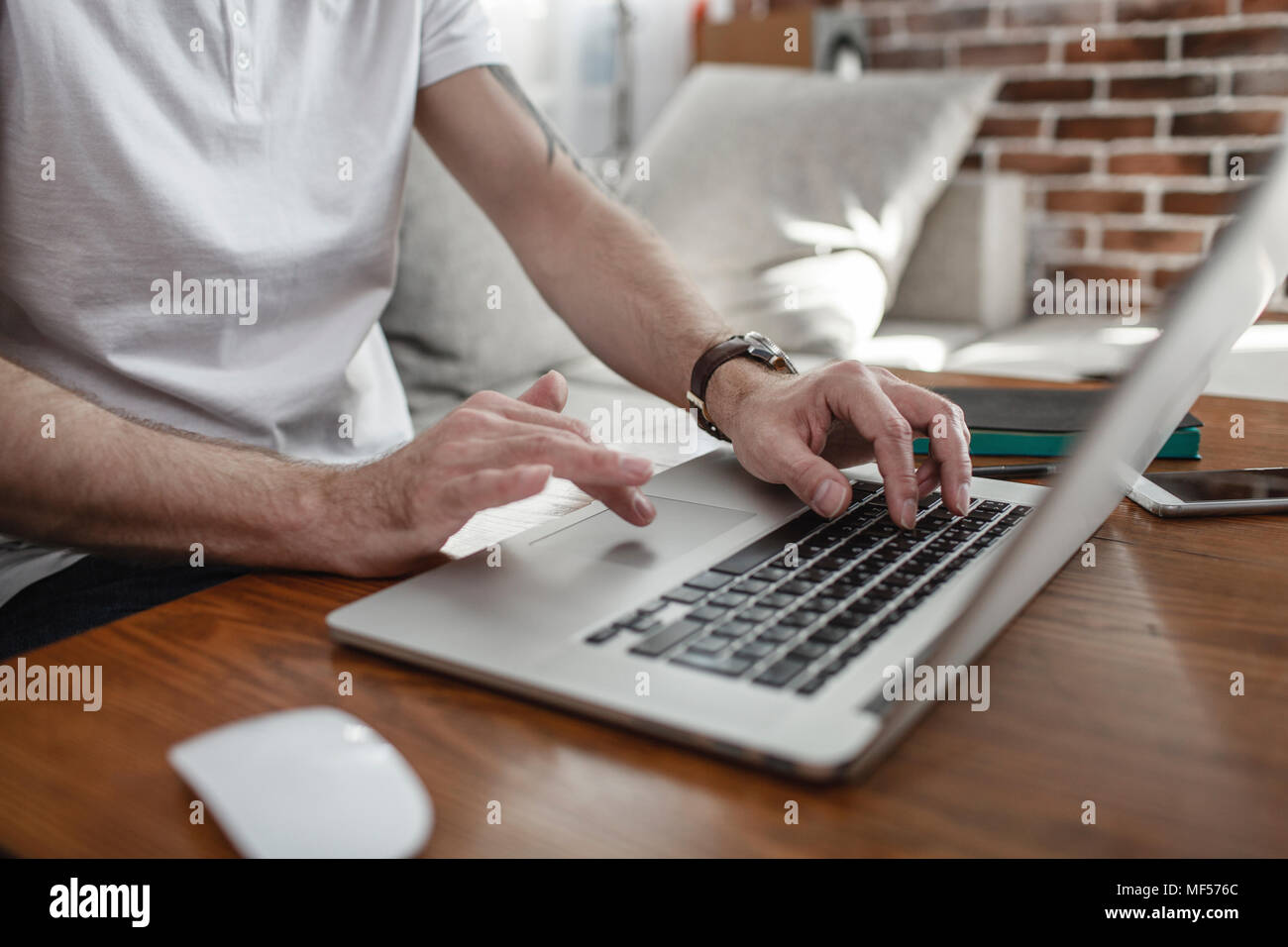 Man's hands on keyboard and touchpad of laptop, partial view Stock Photo