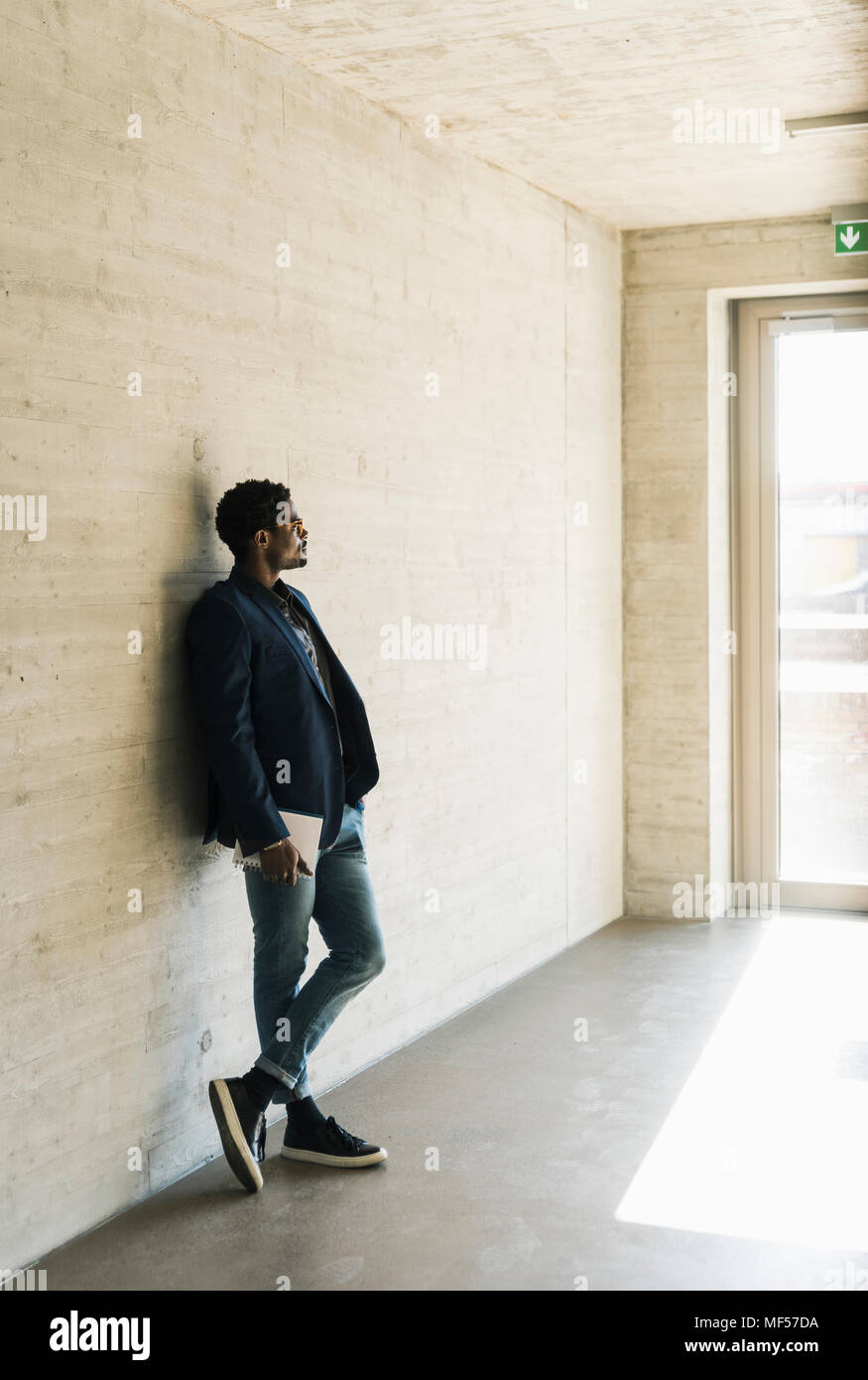 Businessman standing at concrete wall looking away Stock Photo