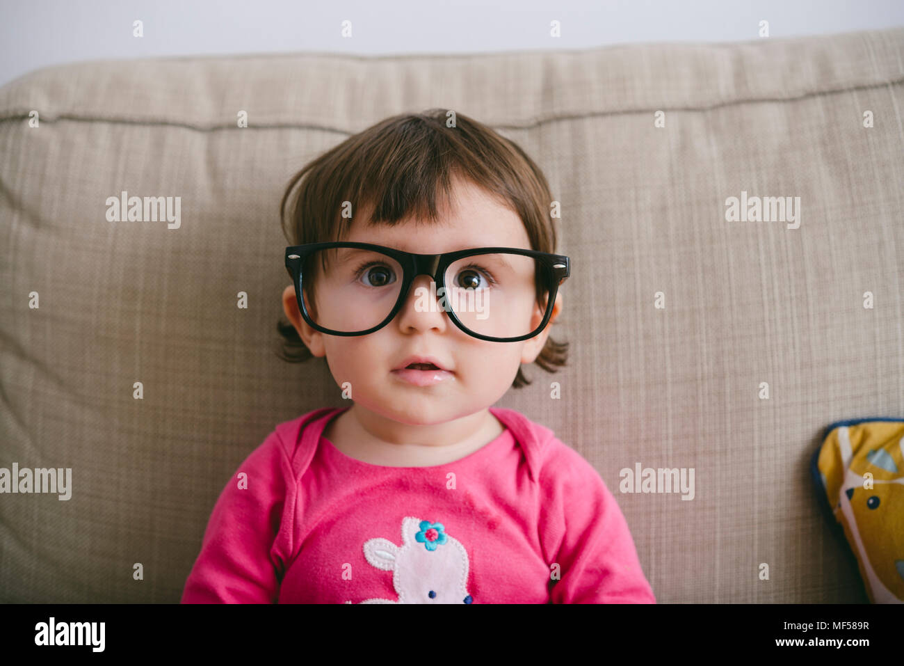 Portrait of staring baby girl wearing oversized glasses Stock Photo