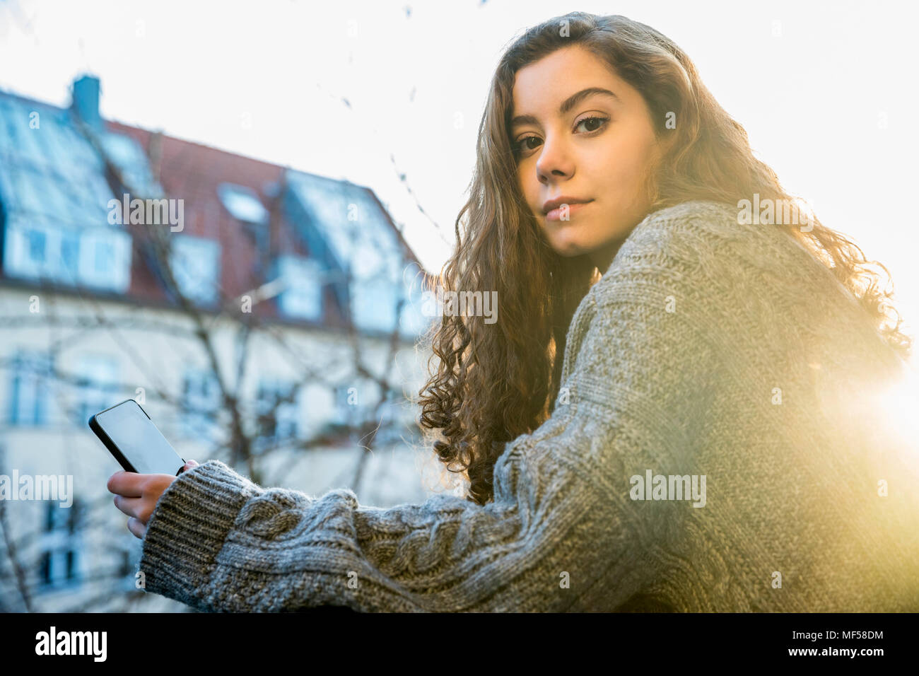 Portrait of teenage girl with smartphone at backlight Stock Photo