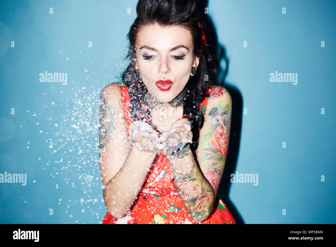 Portrait of tattooed woman blowing artificial snow Stock Photo