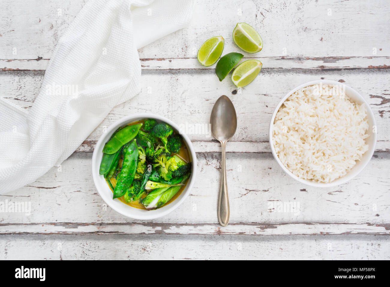 Green thai curry with broccoli, pak choi, snow peas, baby spinach, lime and rice Stock Photo