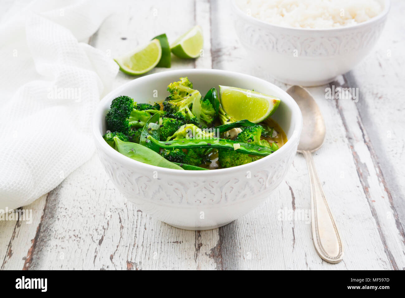 Green thai curry with broccoli, pak choi, snow peas, baby spinach, lime and rice Stock Photo