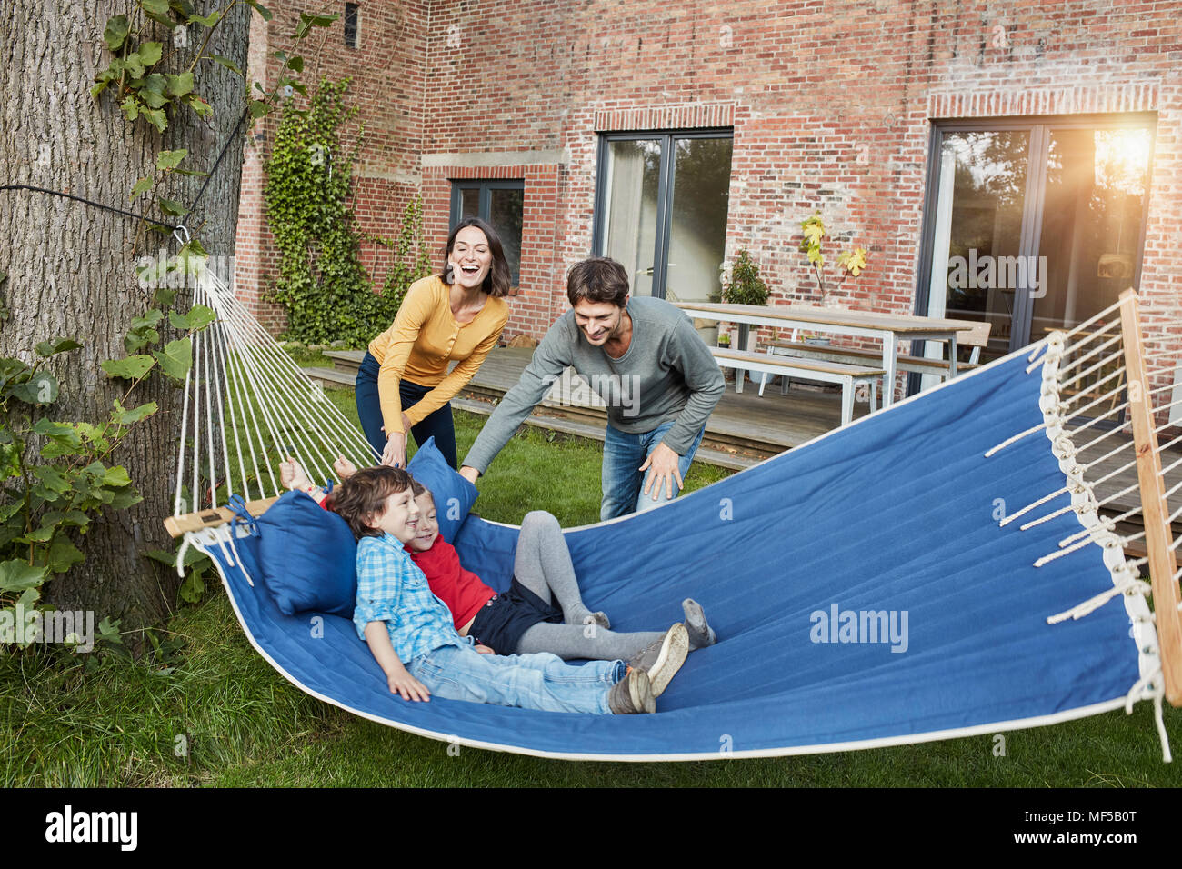 Happy family playing in hammock in garden of their home Stock Photo
