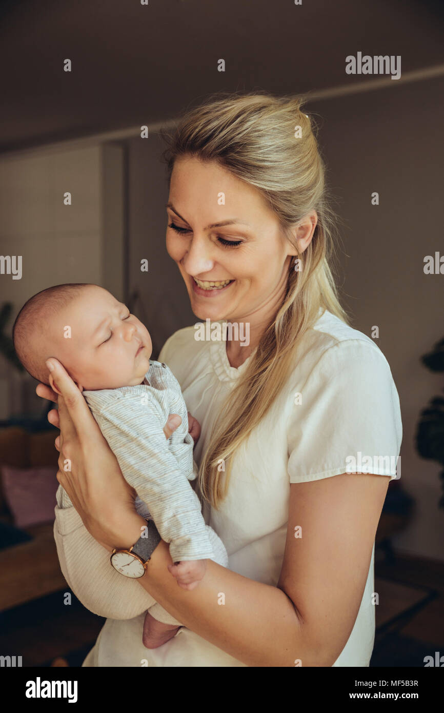 Smiling mother holding sleepy newborn baby Stock Photo