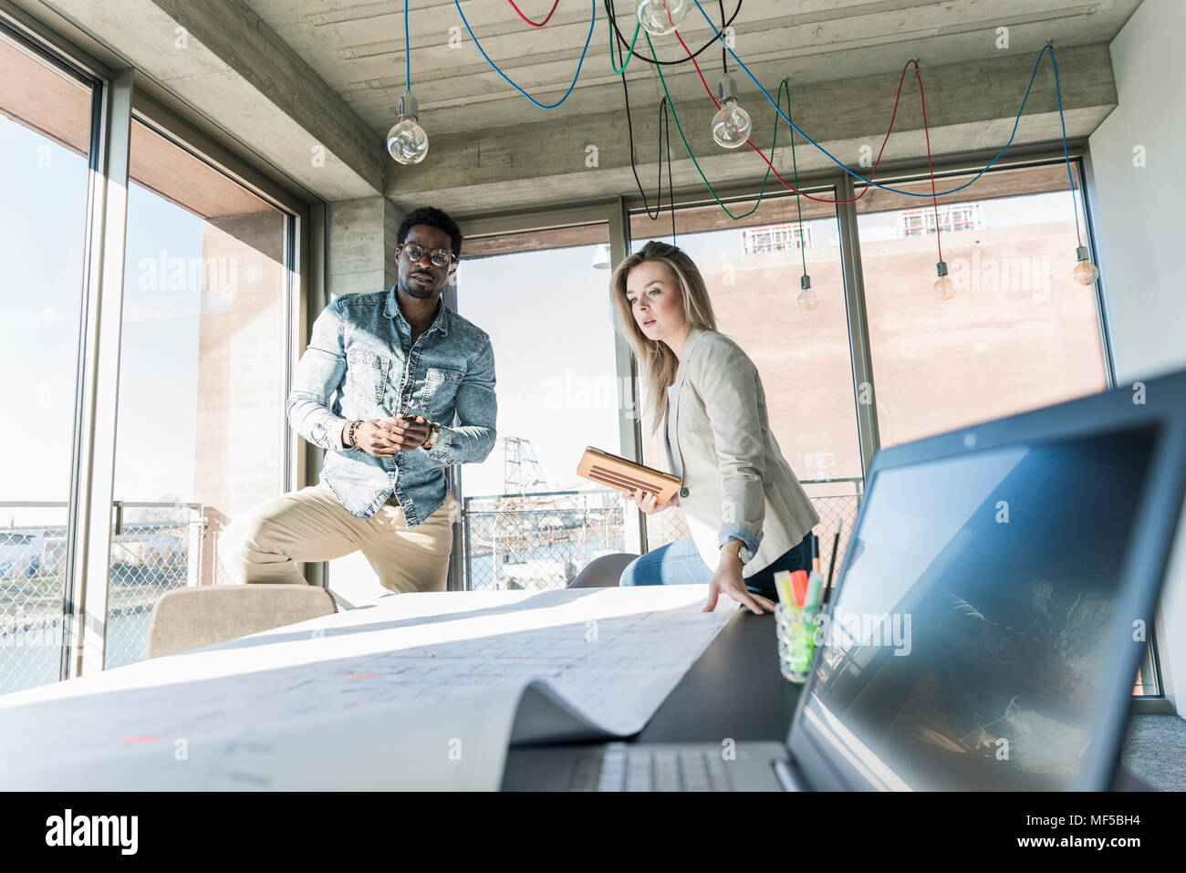 Two colleagues working on plan at table in office Stock Photo
