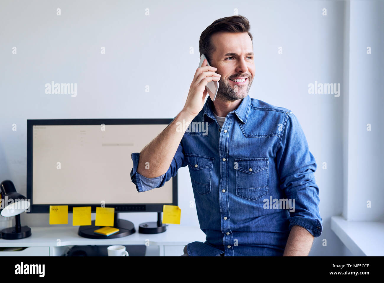 https://c8.alamy.com/comp/MF5CCE/smiling-man-at-desk-in-office-talking-on-the-phone-MF5CCE.jpg