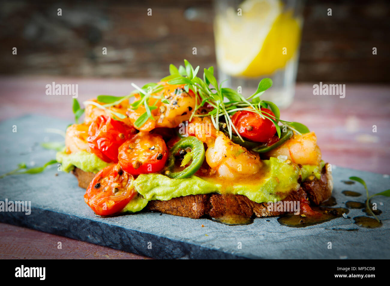 Crostini with shrimps and tomatoes, roasted bread, herbs, avocado cream, sweet chili sauce, jalapenos, cress Stock Photo