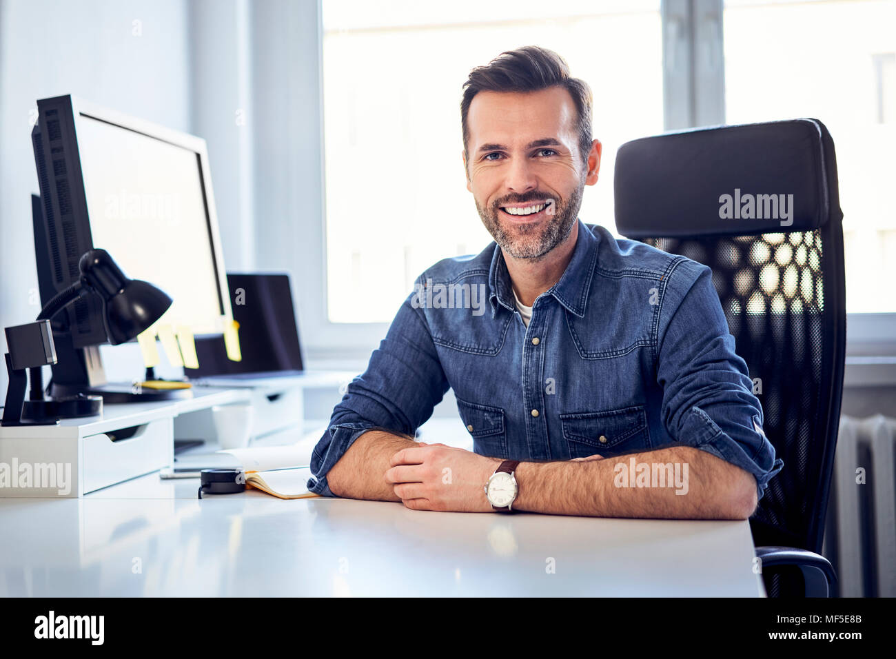 https://c8.alamy.com/comp/MF5E8B/portrait-of-smiling-man-sitting-at-desk-in-office-MF5E8B.jpg