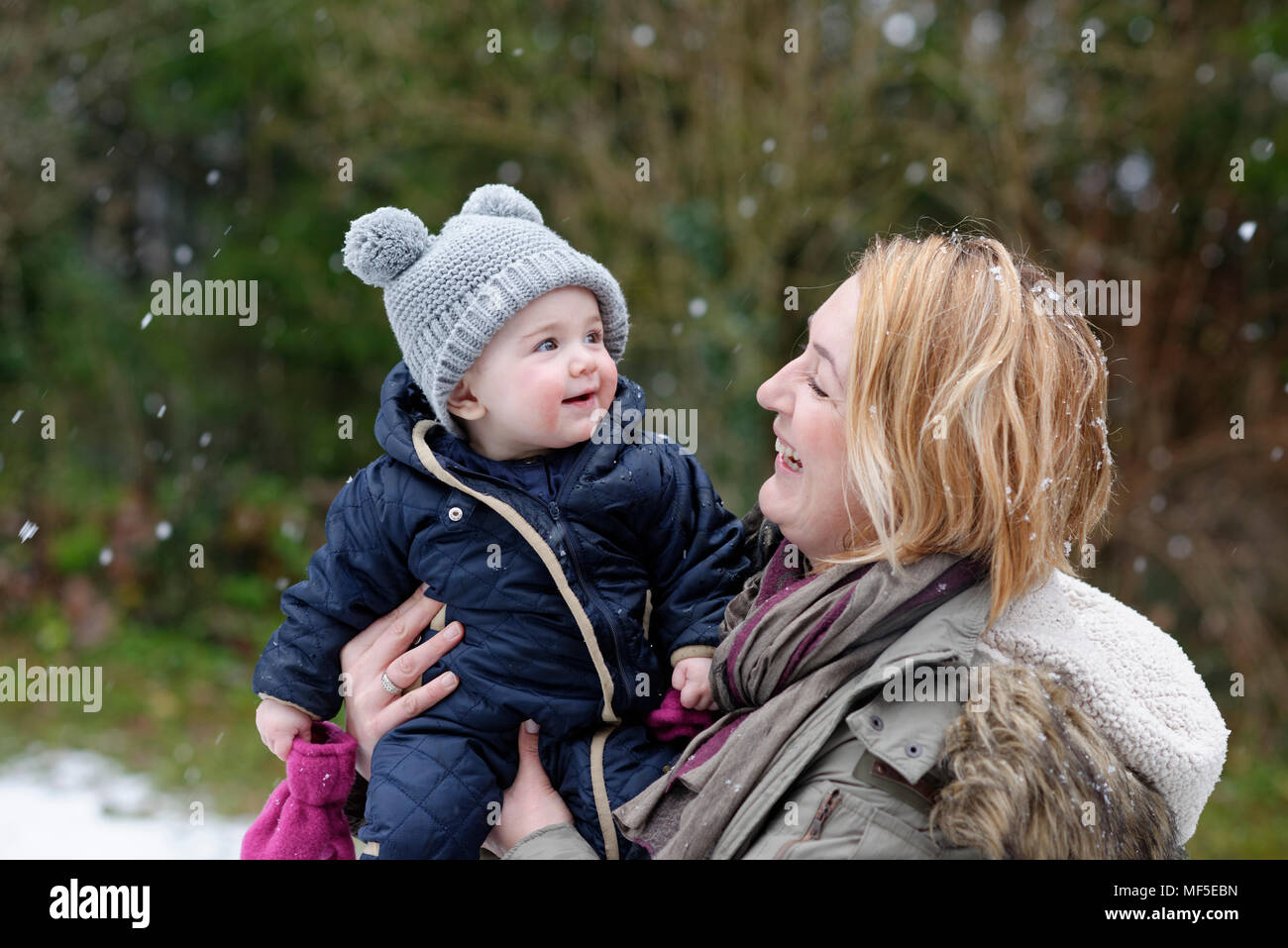 kleines Baby, Mädchen sieht zum ersten Mal Schnee, Schneeflocken, im Winter am arm der Mutter, Oberbayern, Bayern, Deutschland Stock Photo