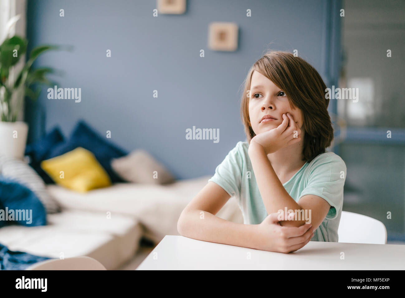 Portrait of sad boy sitting at table at home Stock Photo