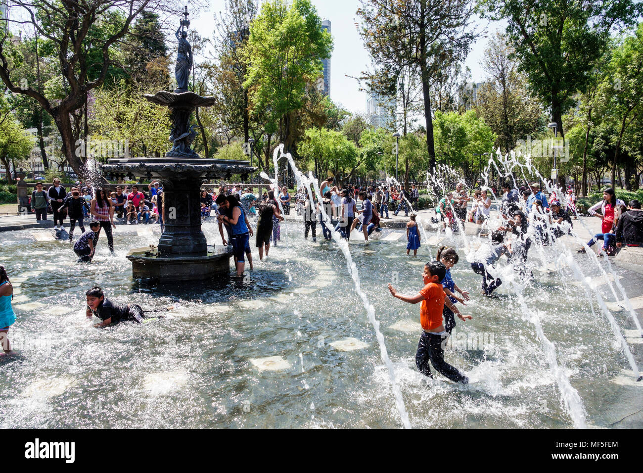 Mexico City,Mexican,Hispanic,historic Center Centre,Central Park Alameda,public urban park,fountain,crowd,water,children,boy boys,male kid kids child Stock Photo