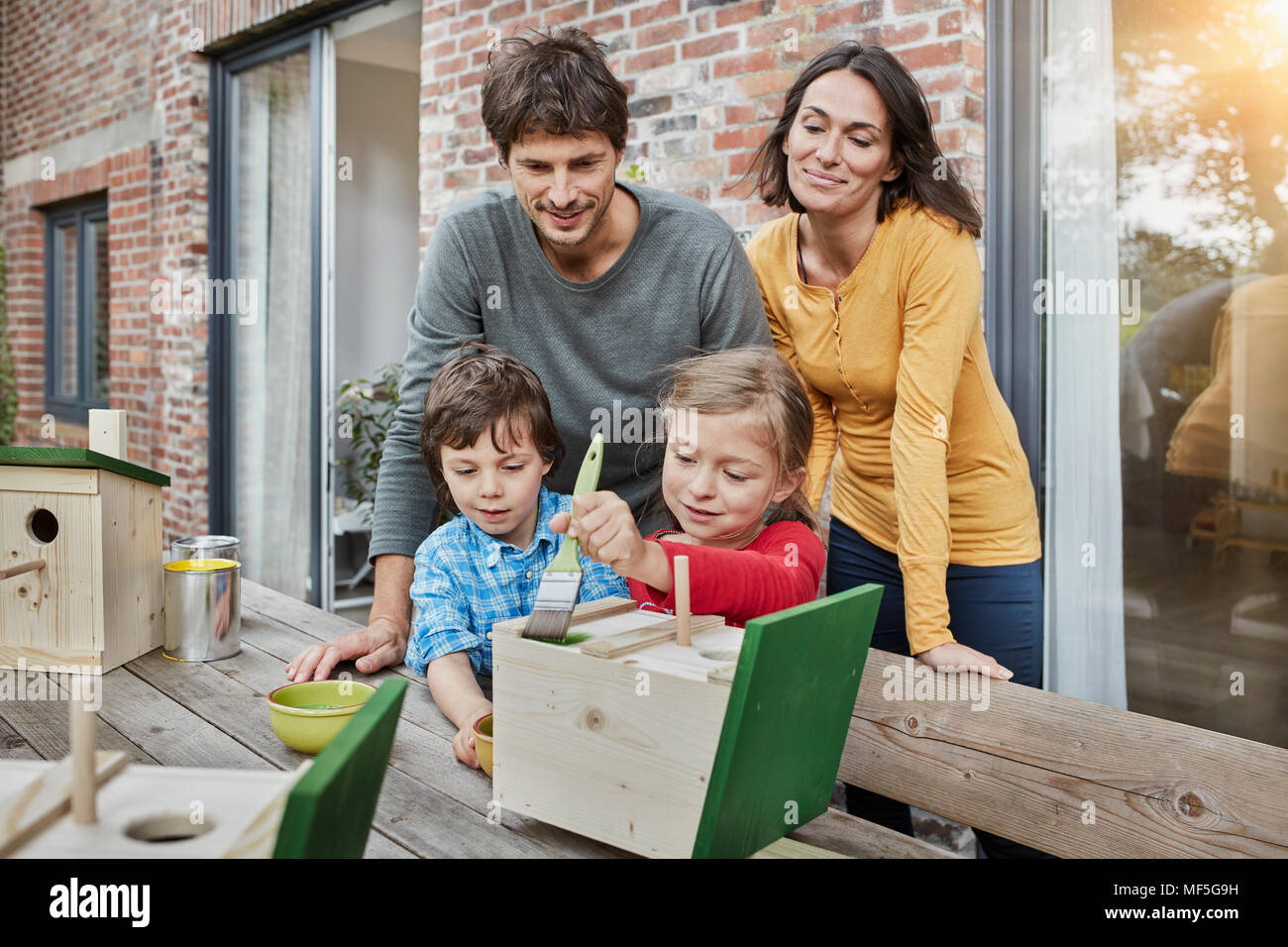 Family working on birdhouse in front of their home Stock Photo
