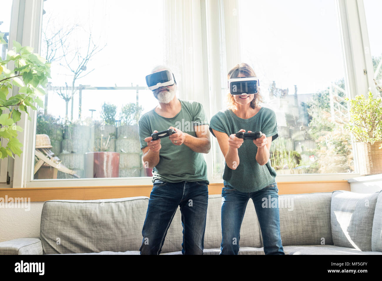 Mature couple in kiving room at home wearing VR glasses playing video game  Stock Photo - Alamy