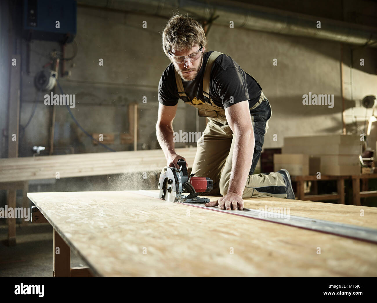 Carpenter sawing wood with handsaw Stock Photo
