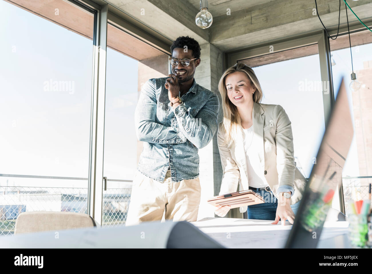 Two colleagues working on plan at table in office Stock Photo
