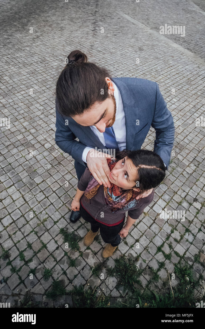 Businessman standing on cobblestones looking at woman with hand on her shoulders Stock Photo