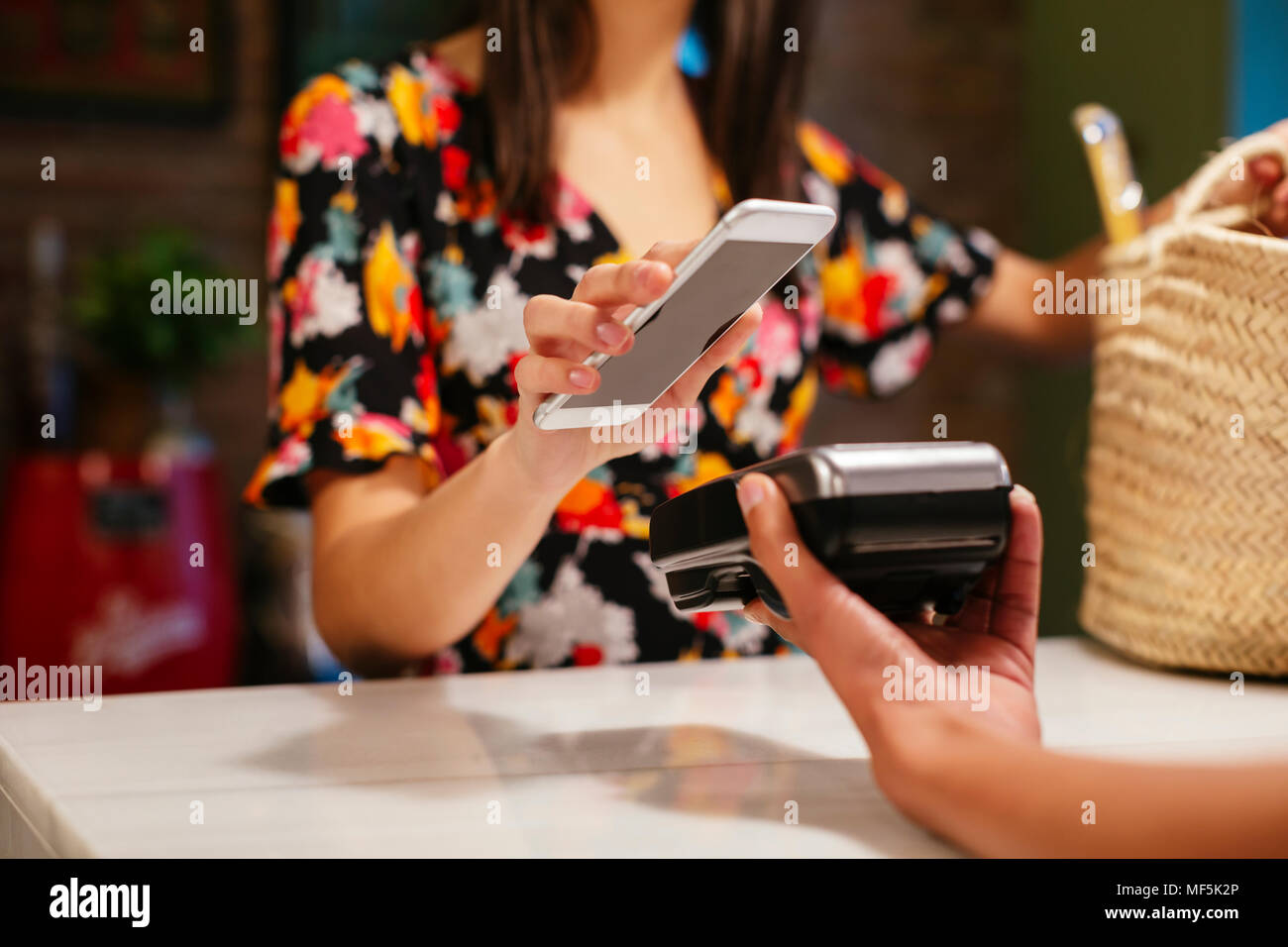 Close-up of customer paying cashless with smartphone at counter of a store Stock Photo