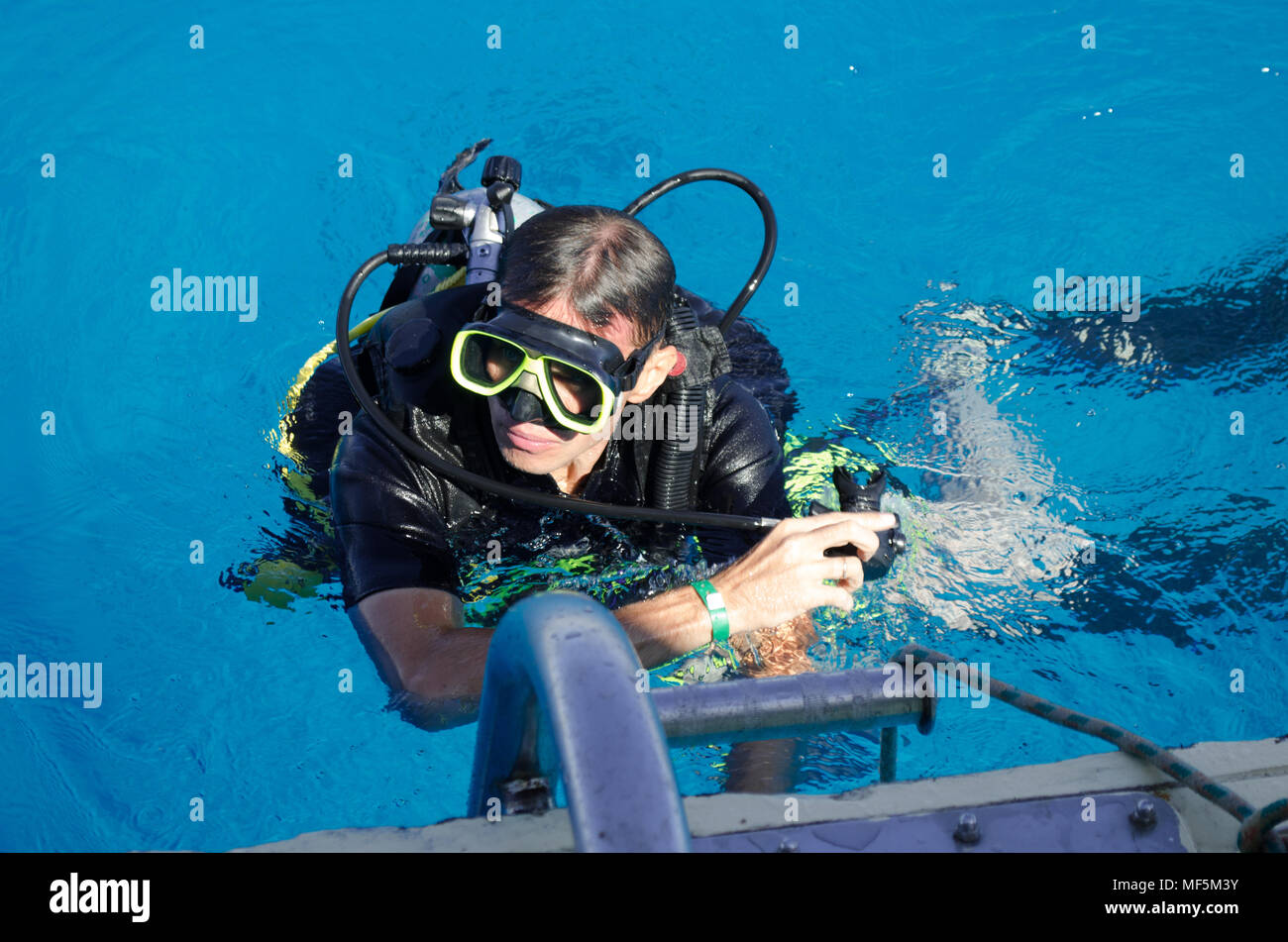 A man with an aqualung floats in the blue water of the sea Stock Photo