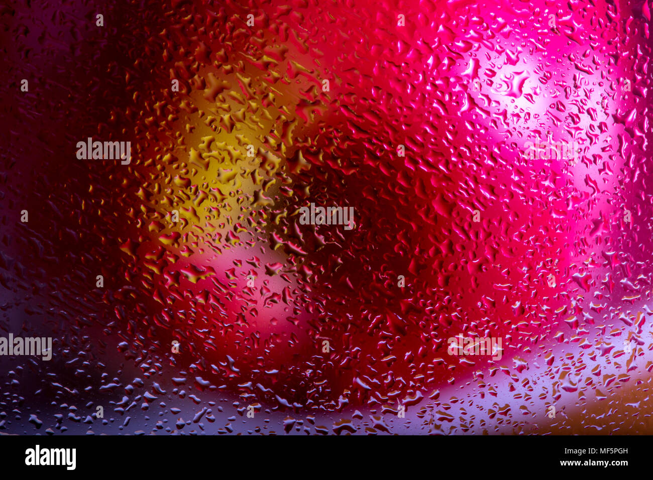 Pink lady apple behind wet glass, obscured by water droplets. Interesting screen saver design. Abstract / background. Stock Photo