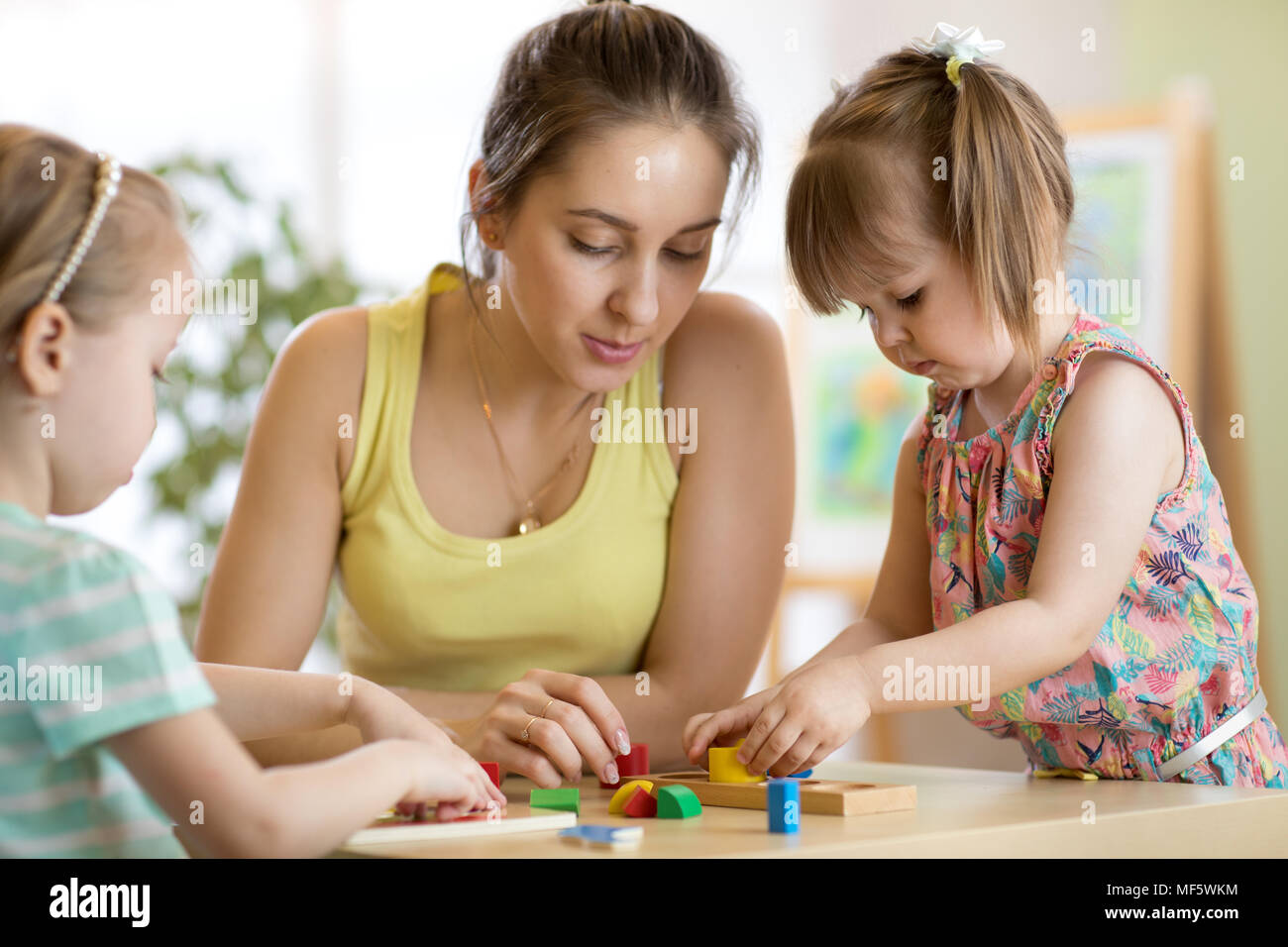 Children starring teacher play with educational toys, stack and arrange