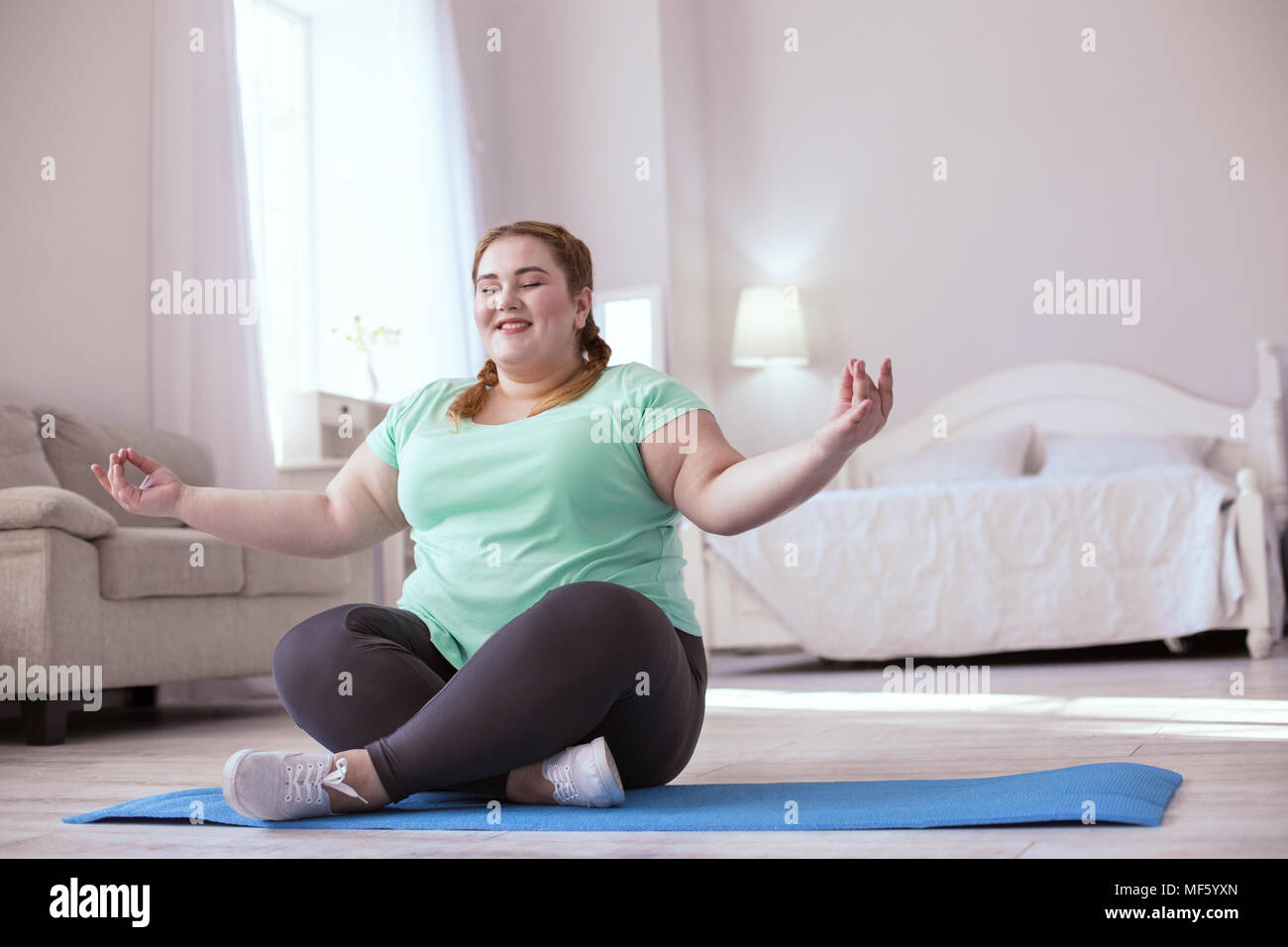 Happy red-head woman meditating on the yoga mat Stock Photo
