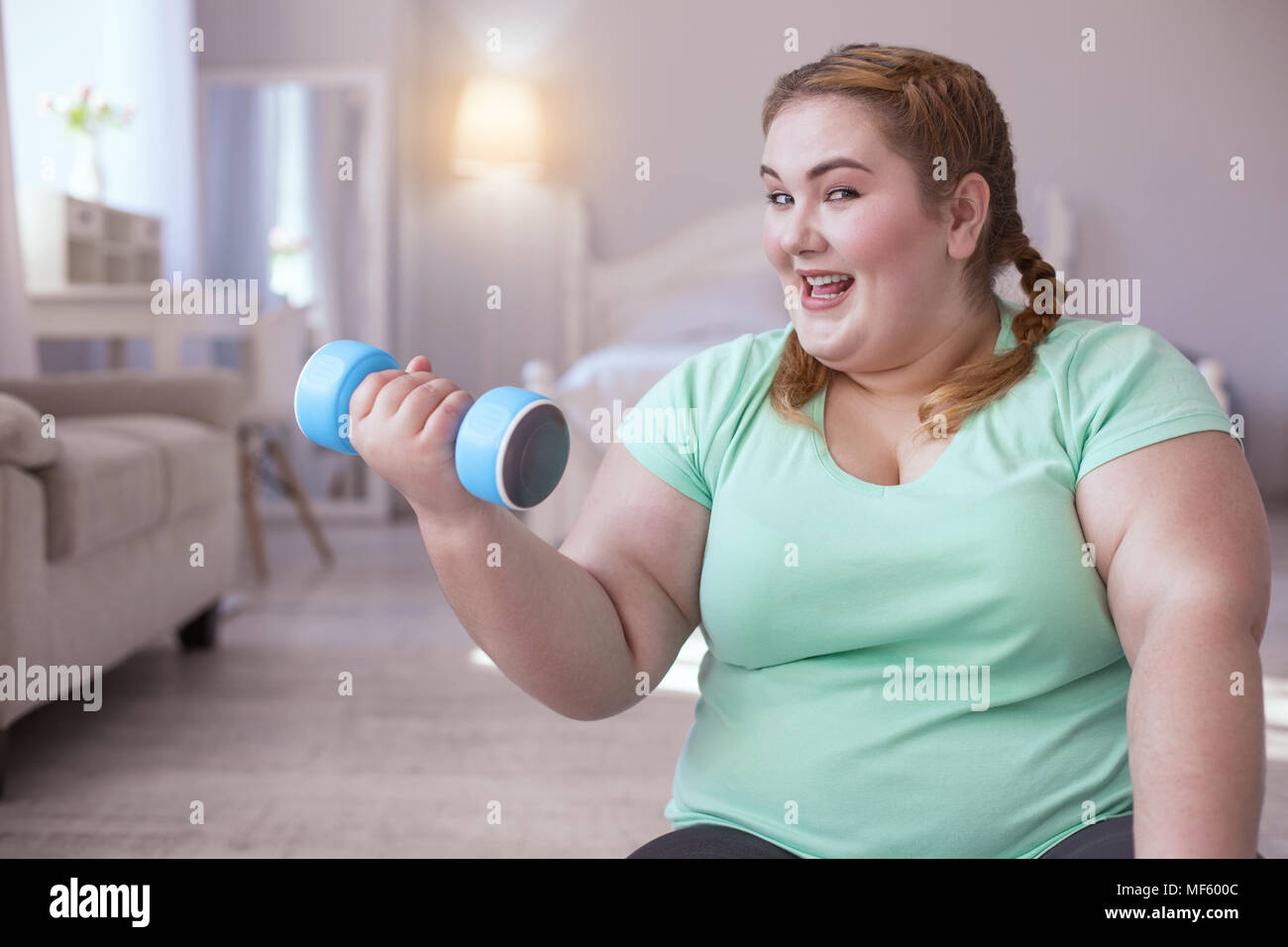 Amused young woman exercising with dumbbells Stock Photo