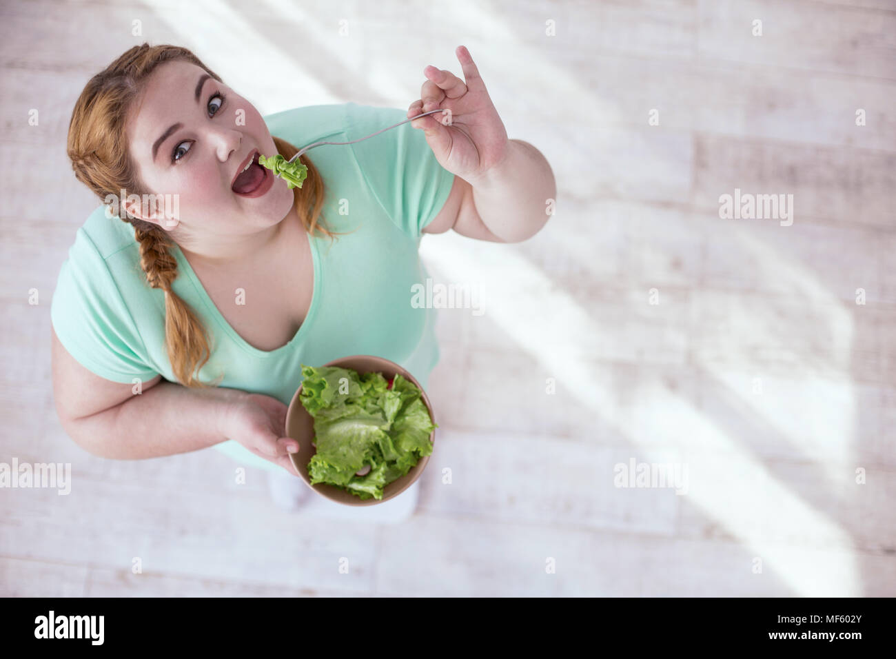Plump young woman eating salad Stock Photo