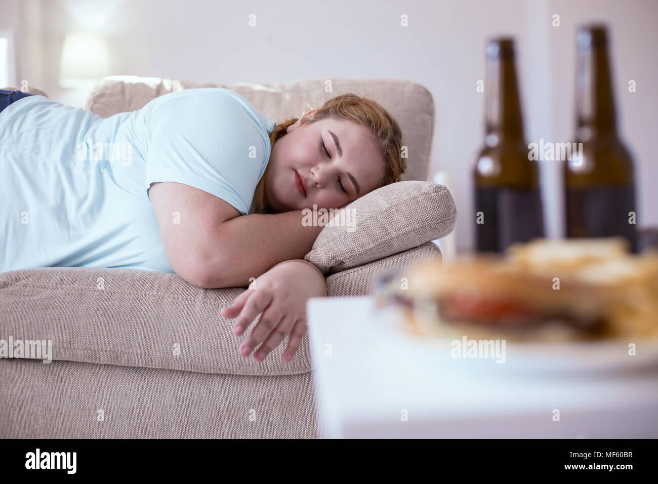 Lazy plump woman sleeping on the couch Stock Photo