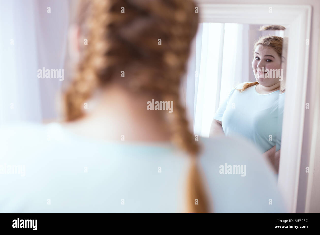 Delighted young woman looking in the mirror Stock Photo