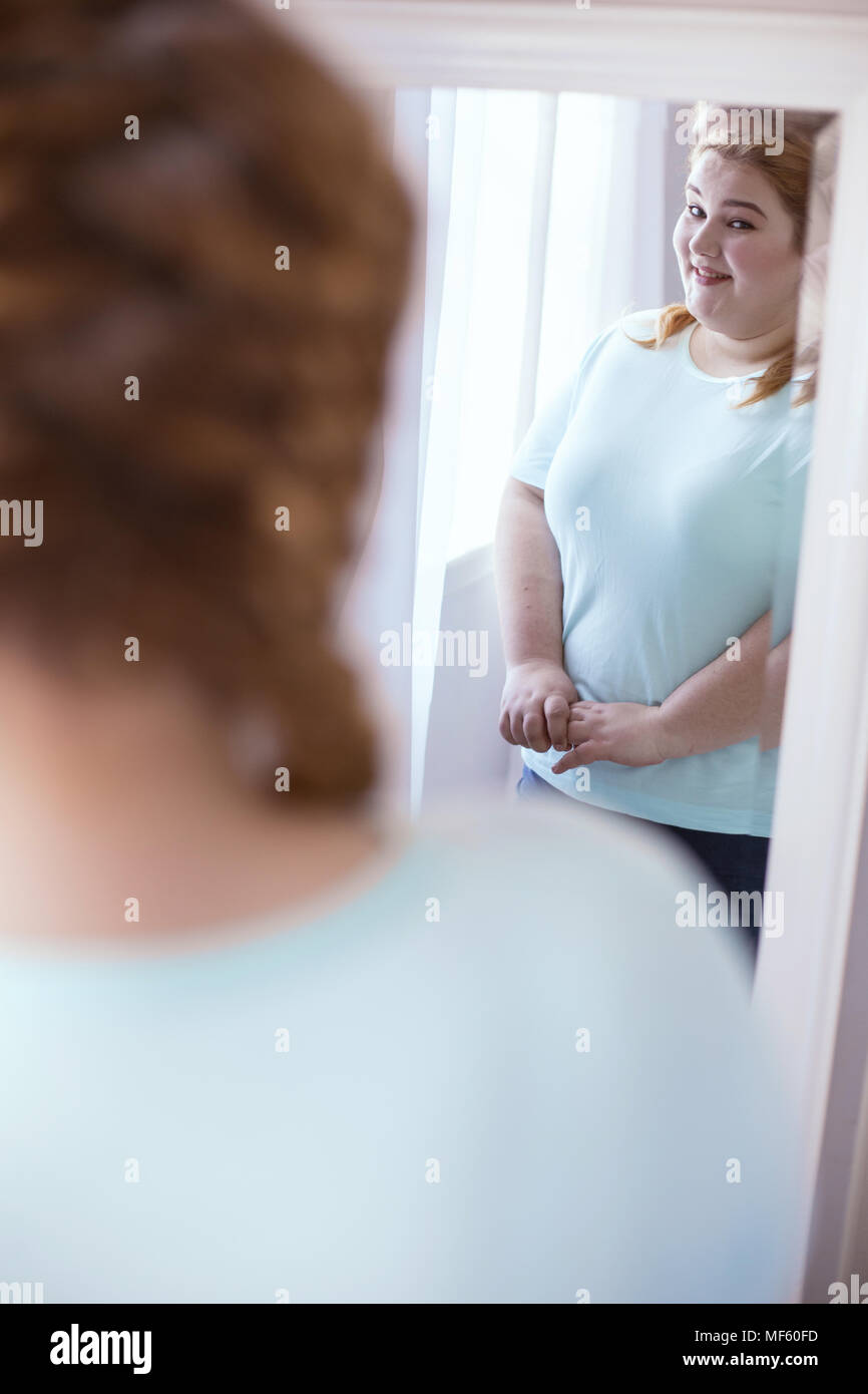 Pleasant shy woman standing next to the mirror Stock Photo
