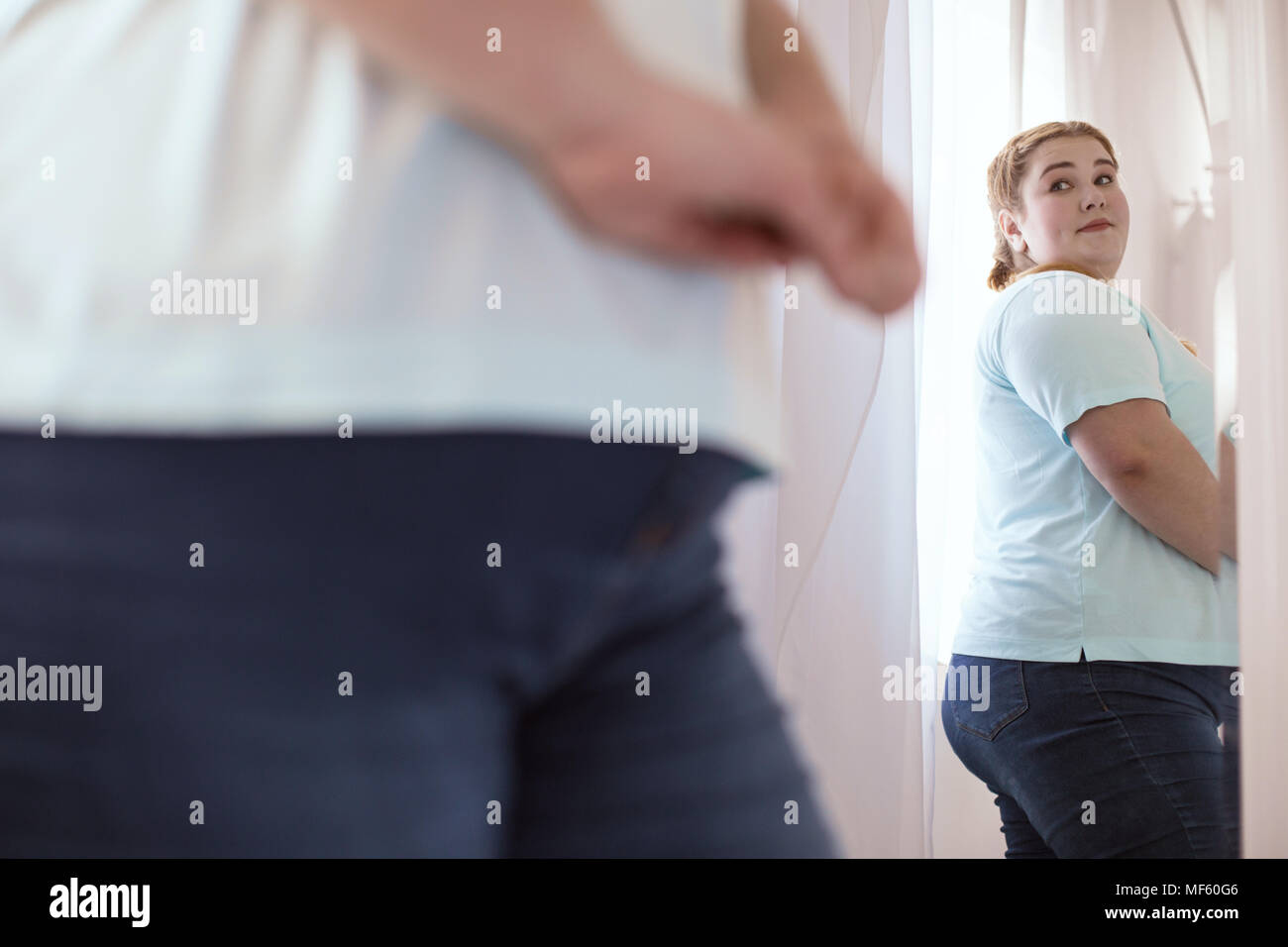 Nice young woman evaluating herself in the mirror Stock Photo