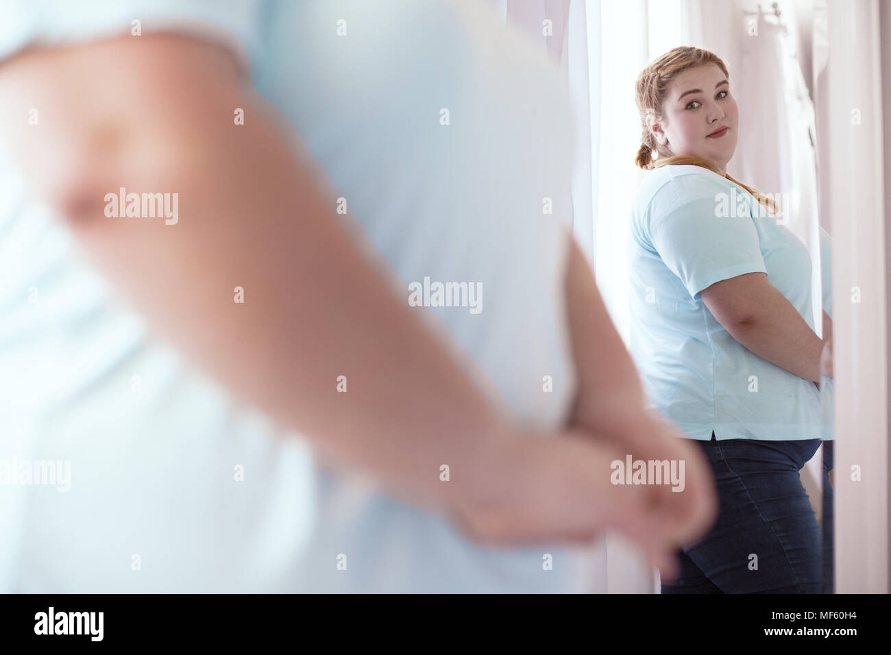 Disappointed young woman looking in the mirror Stock Photo