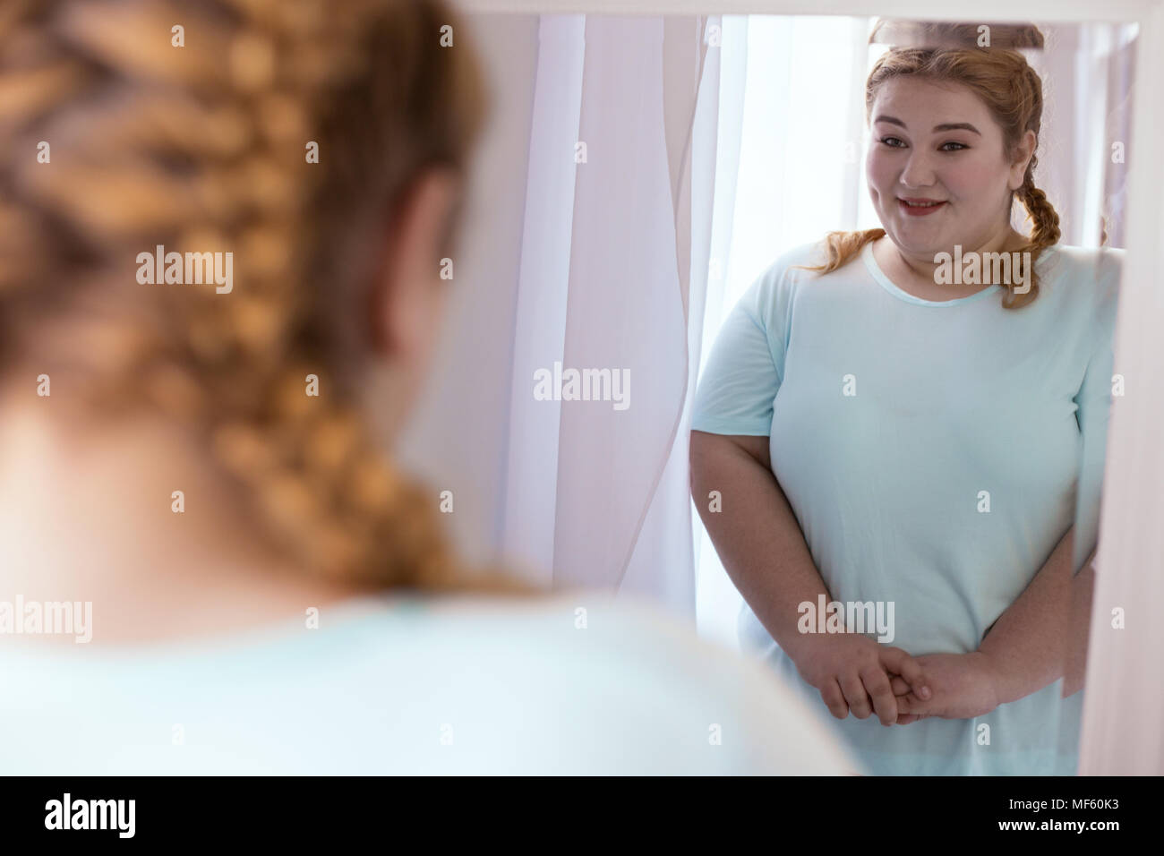 Pleasant good looking woman looking in the mirror Stock Photo