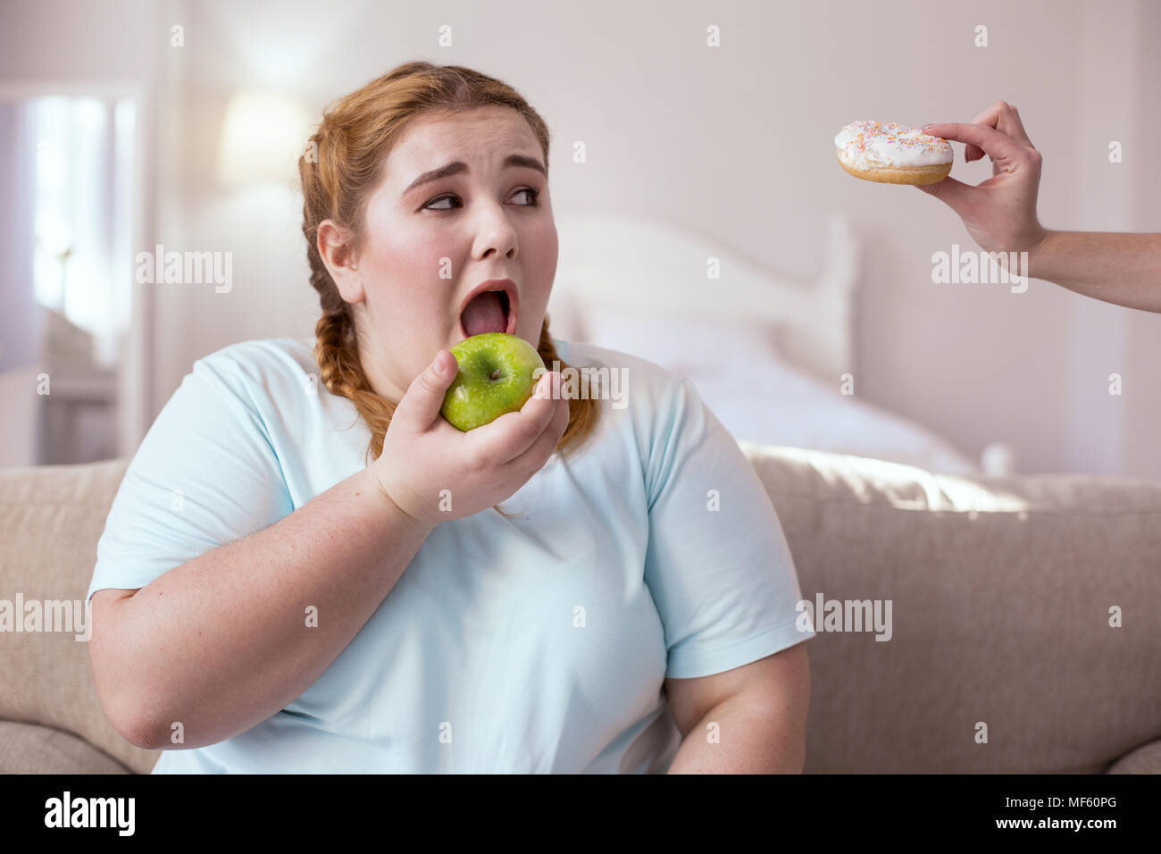 Plump woman eating appealing apple Stock Photo