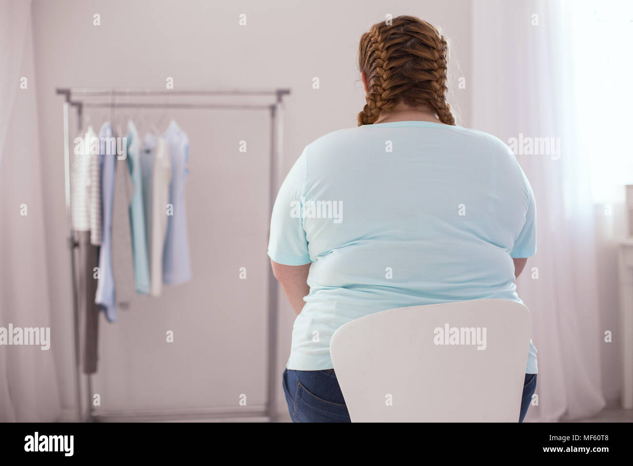 Stout young woman sitting on the chair Stock Photo