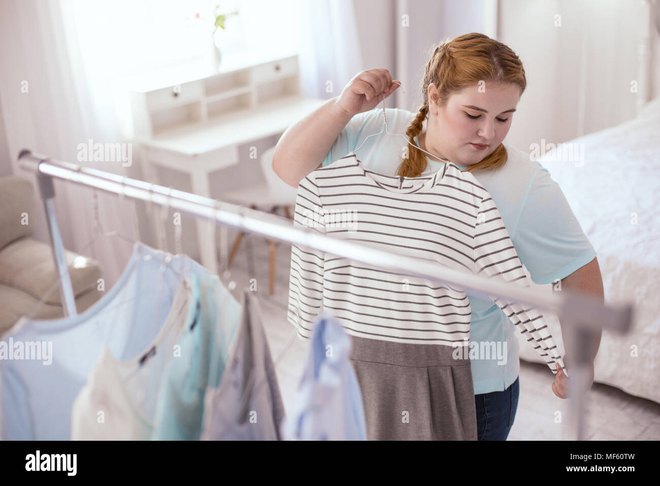 Chubby young woman trying on dresses Stock Photo