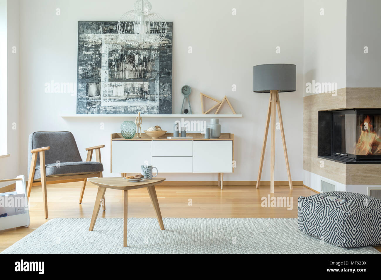 Grey armchair next to a wooden table in scandi living room interior ... - Gray And White Scandi Living Room Interior