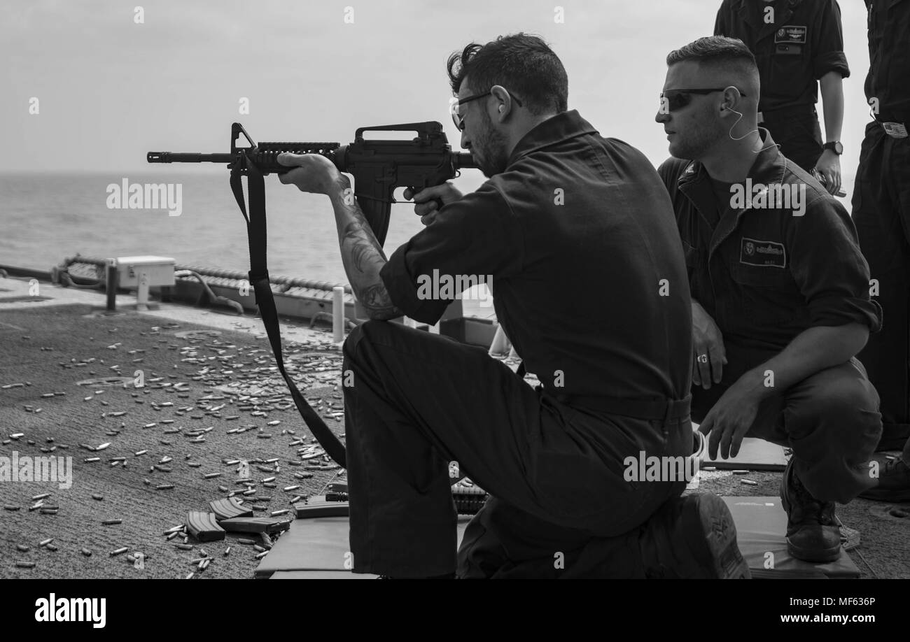 180418-N-DO281-0256 MEDITERRANEAN SEA (April 18, 2018) Interior Communications Electrician 3rd Class Austyn Hanif, left, fires a M-16 rifle and Gunner's Mate 2nd Class Billy Riley, right, stands line coach during a live-fire exercise aboard the guided-missile cruiser USS Monterey (CG 61), April 18, 2018. Monterey, home-ported in Norfolk, Virginia, is conducting operations in the U.S. 6th Fleet area of operations in support of U.S. national security interest in Europe. (U.S. Navy photo by Mass Communication Specialist Seaman Trey Fowler). () Stock Photo