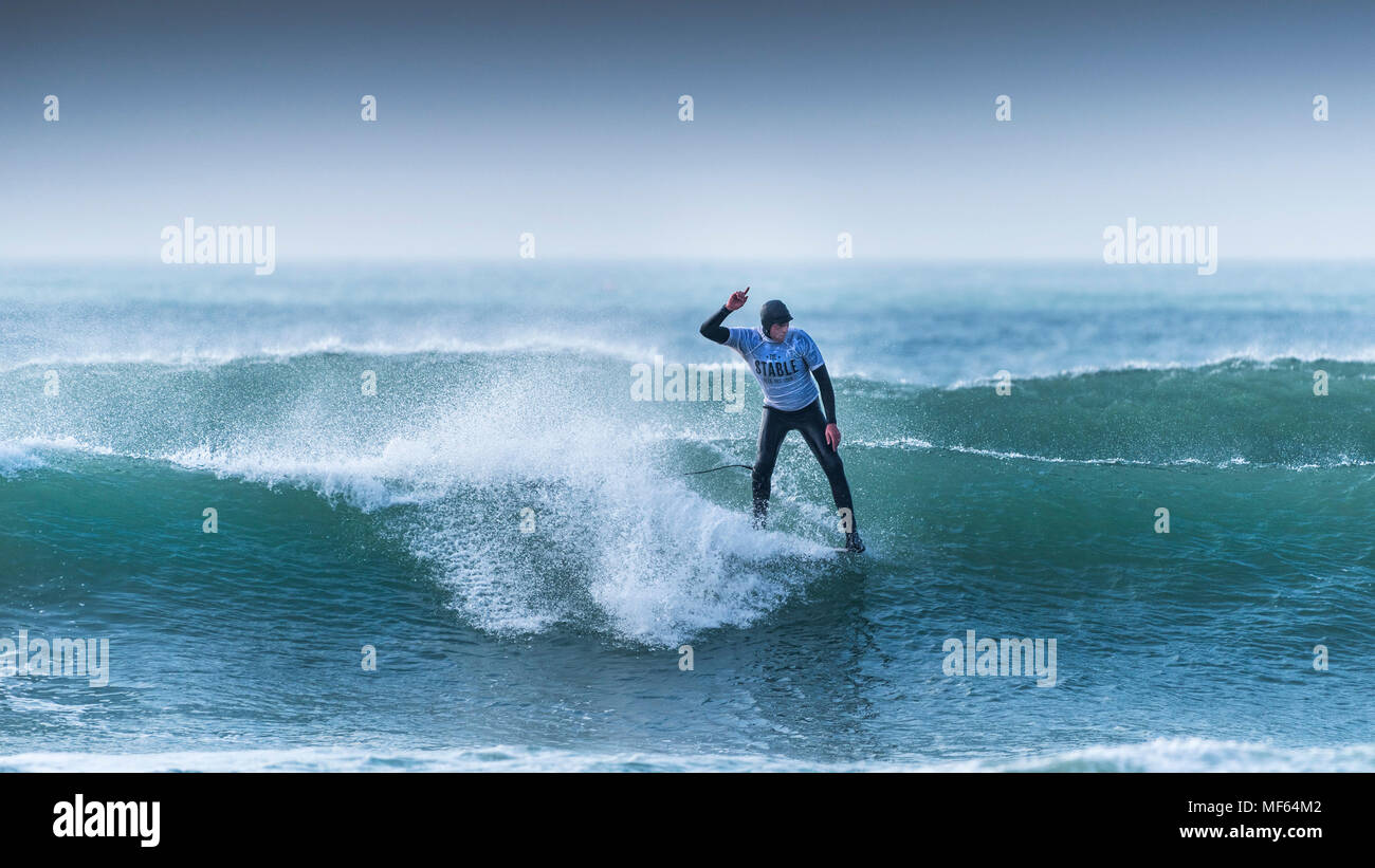A surfer competing in a longboard surfing festival at Fistral Beach in