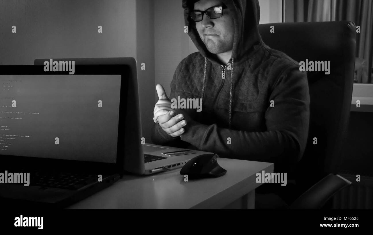 Black and white image of hacker smiling after stealing money from internet Stock Photo
