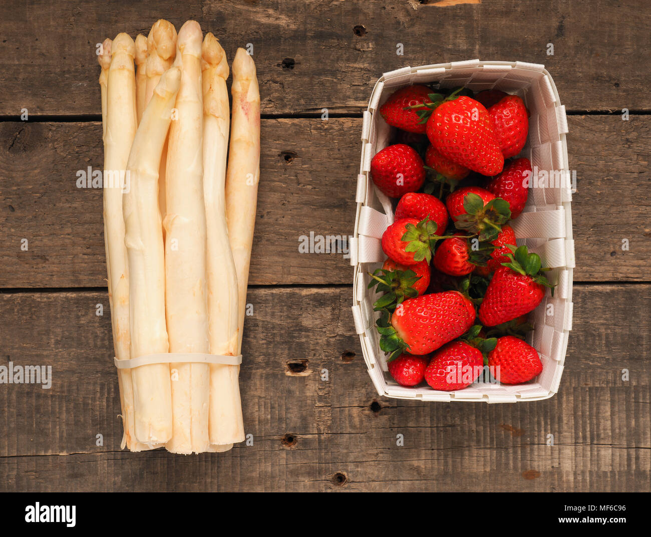 Fresh organic strawberries and white asparagus on a rustic wooden table Stock Photo