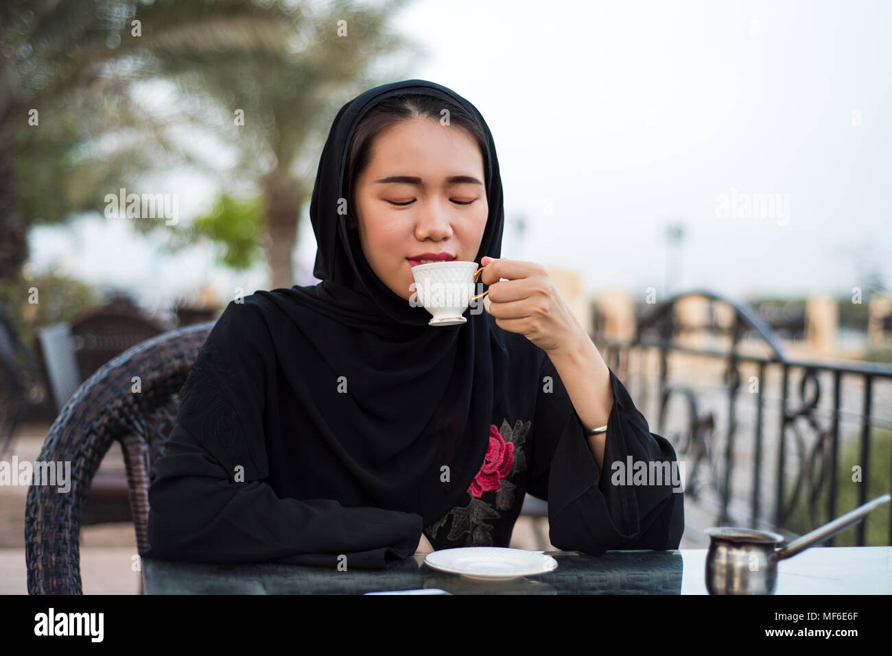 Muslim woman having a cup of coffee in a bar outdoors Stock Photo