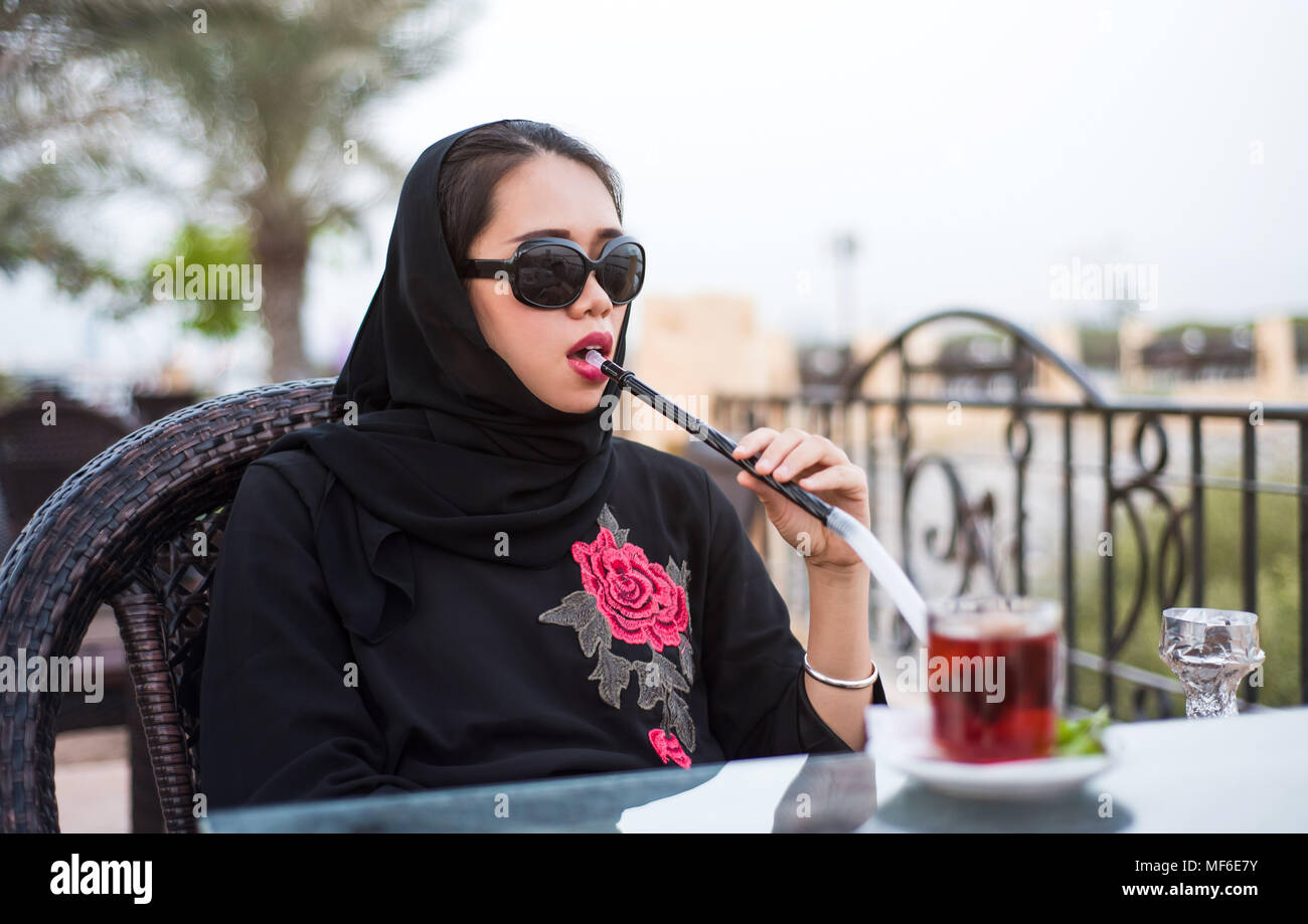Muslim woman smoking shisha in a bar outdoors Stock Photo